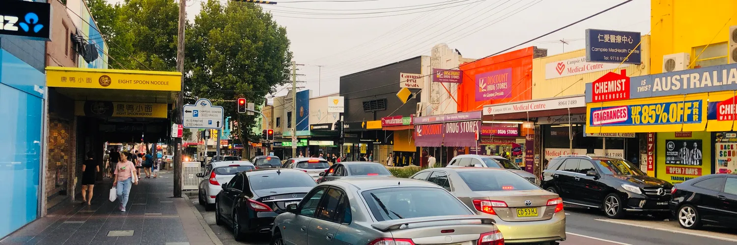 Shops, signs and parked cars along Beamish Street in Campsie, Sydney