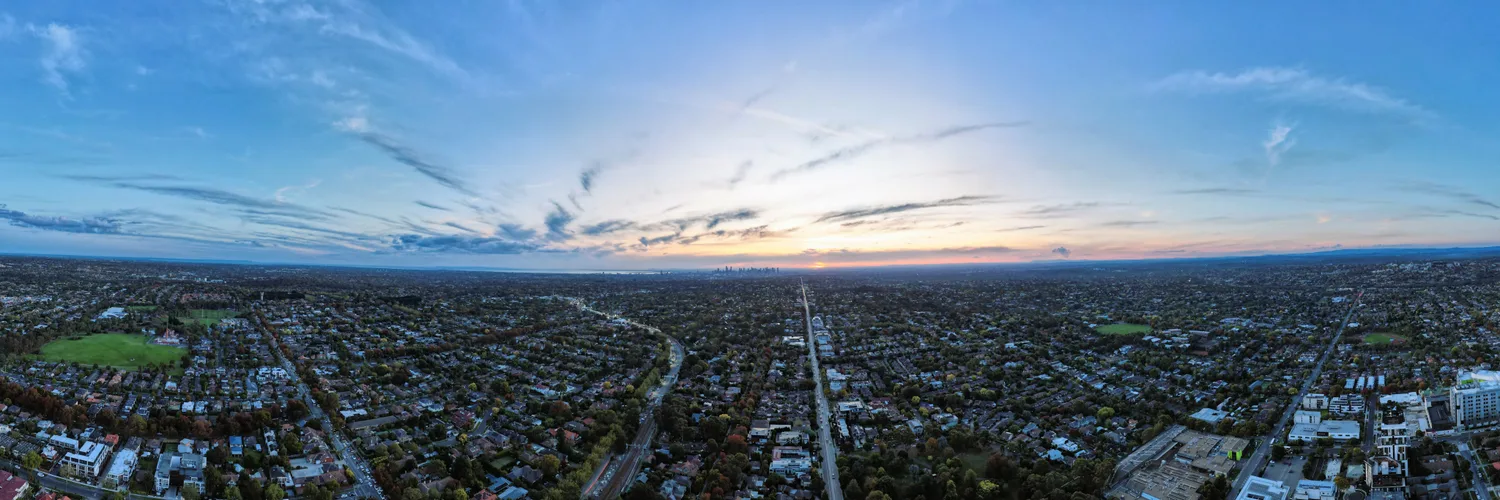 Aerial view over Melbourne suburban rooftops towards the city skyline