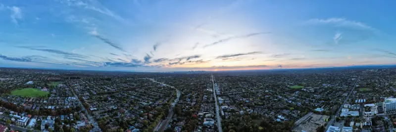 Aerial view over Melbourne suburban rooftops towards the city skyline