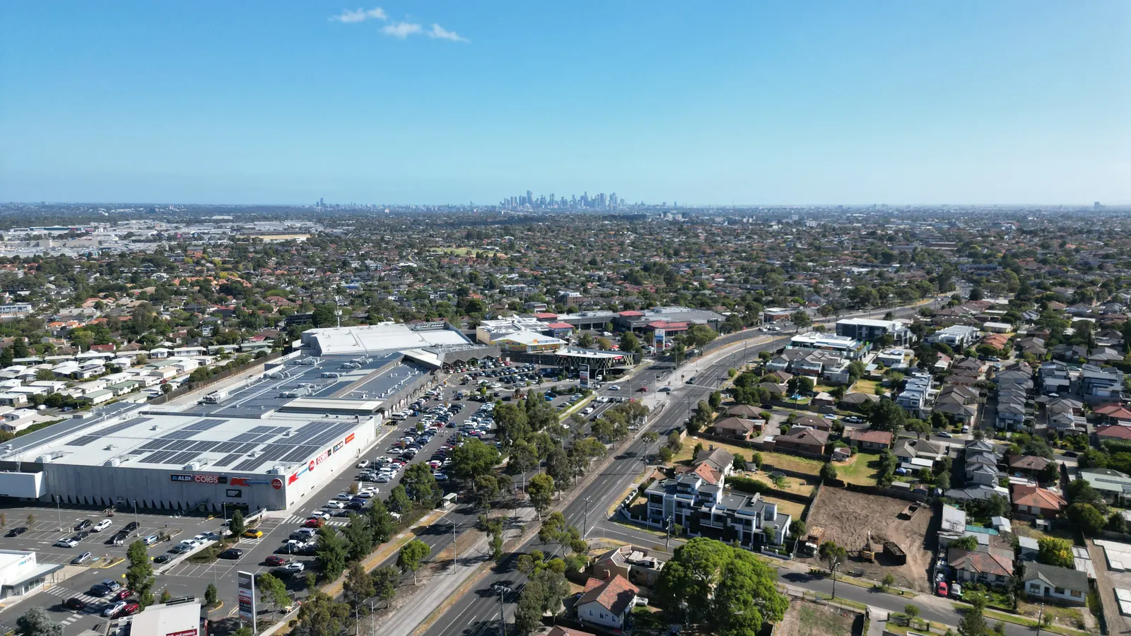 Aerial view of Summerhill Shopping Centre in Reservoir, Melbourne, with the city skyline on the horizon under a clear blue sky