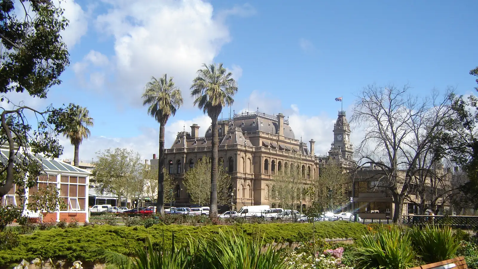 Bendigo Law Courts seen across the gardens of Rosalind Park with palm trees and flowers