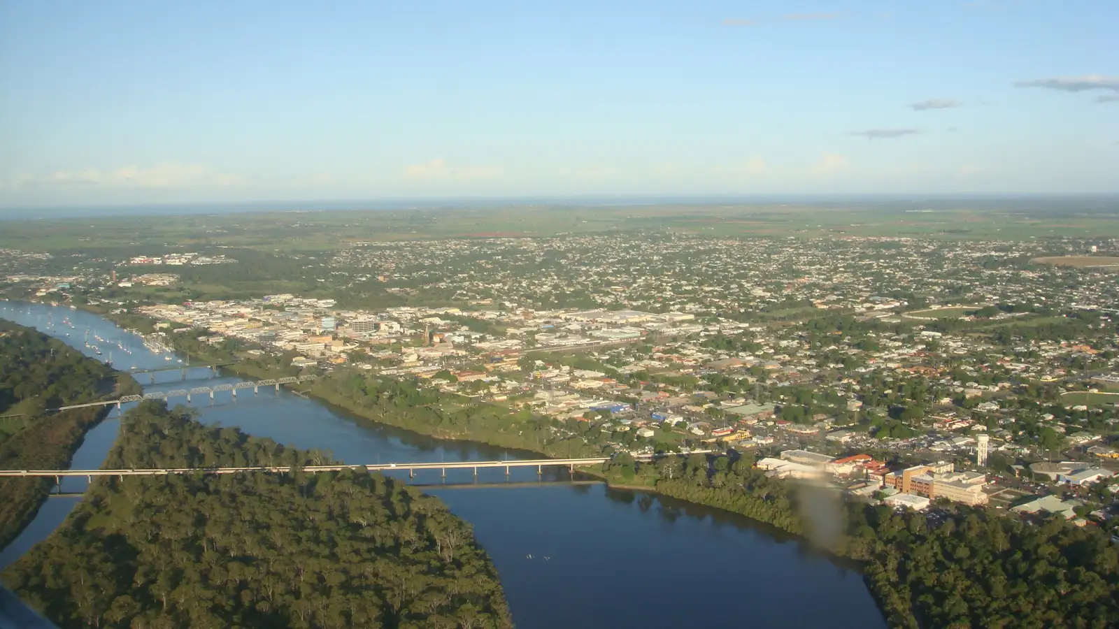 Aerial view of Bundaberg and the Burnett River winding past the city on a clear day