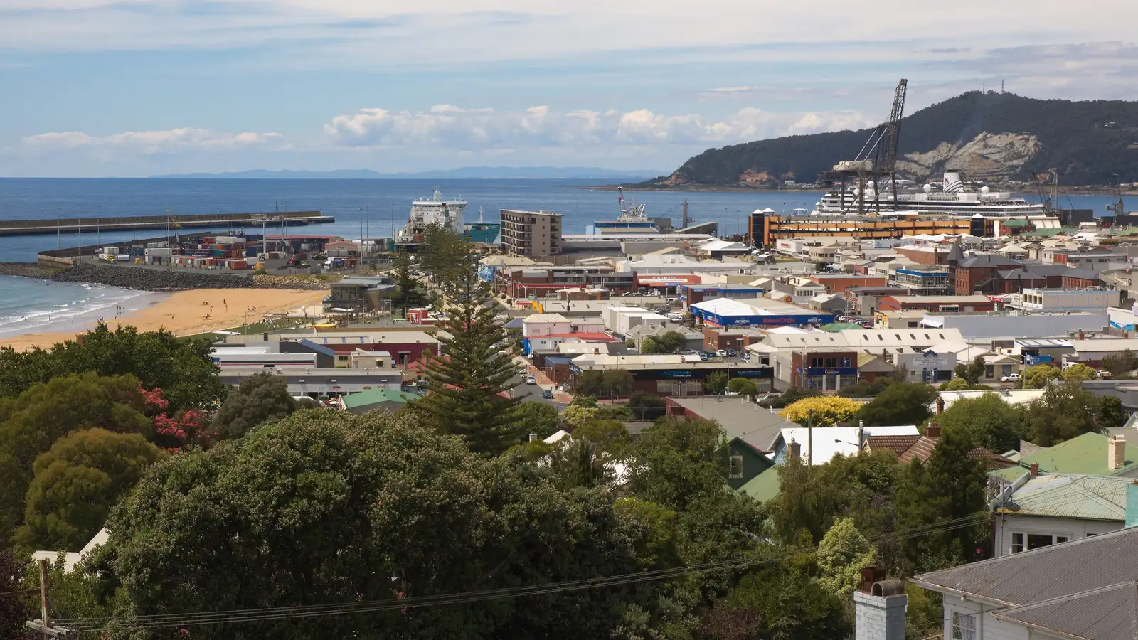 Burnie city centre, West Beach and the port with Round Hill behind, under a partly cloudy sky