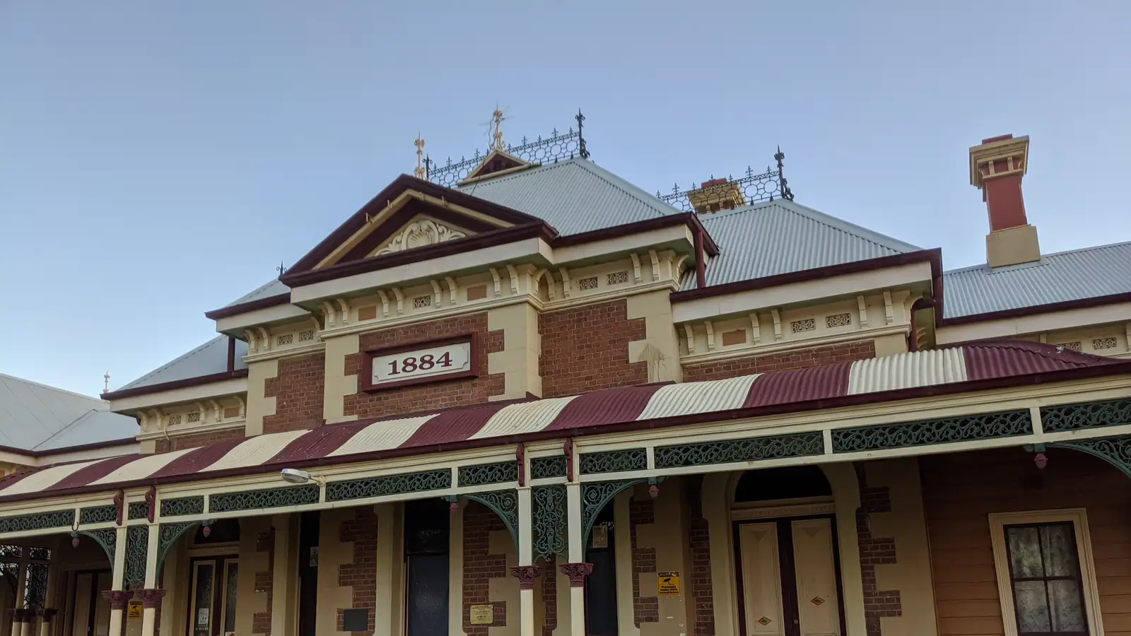 Mudgee's ornate brick heritage railway station building, dated 1884, under a blue sky