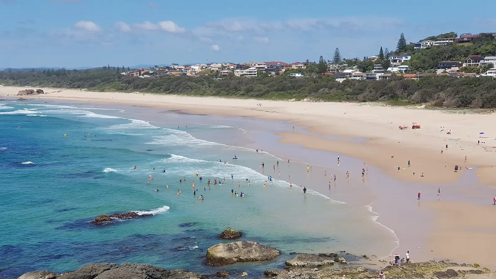Lighthouse Beach at Port Macquarie with turquoise water, rocks and beachgoers under a blue sky