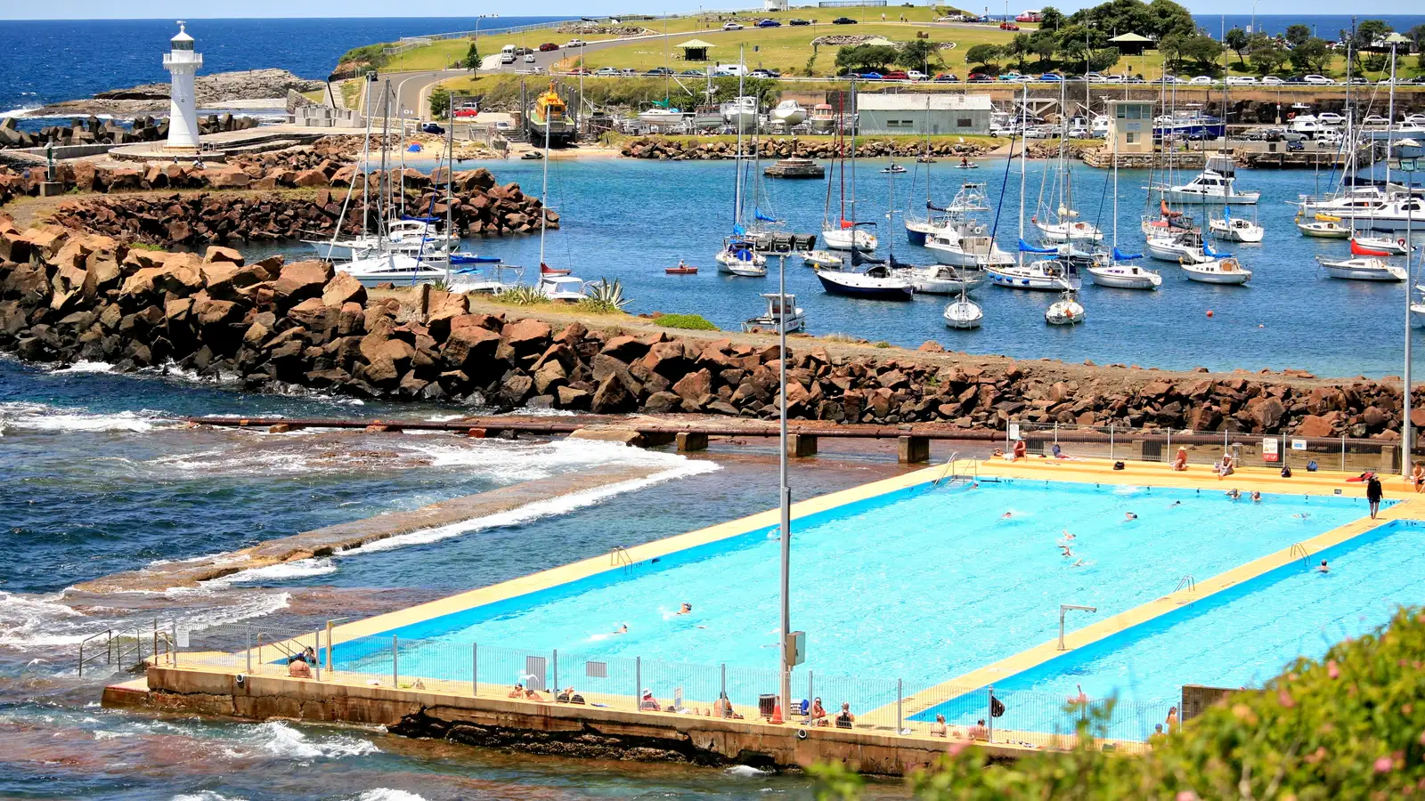 Wollongong Harbour with moored boats, the ocean pool and the Breakwater Lighthouse